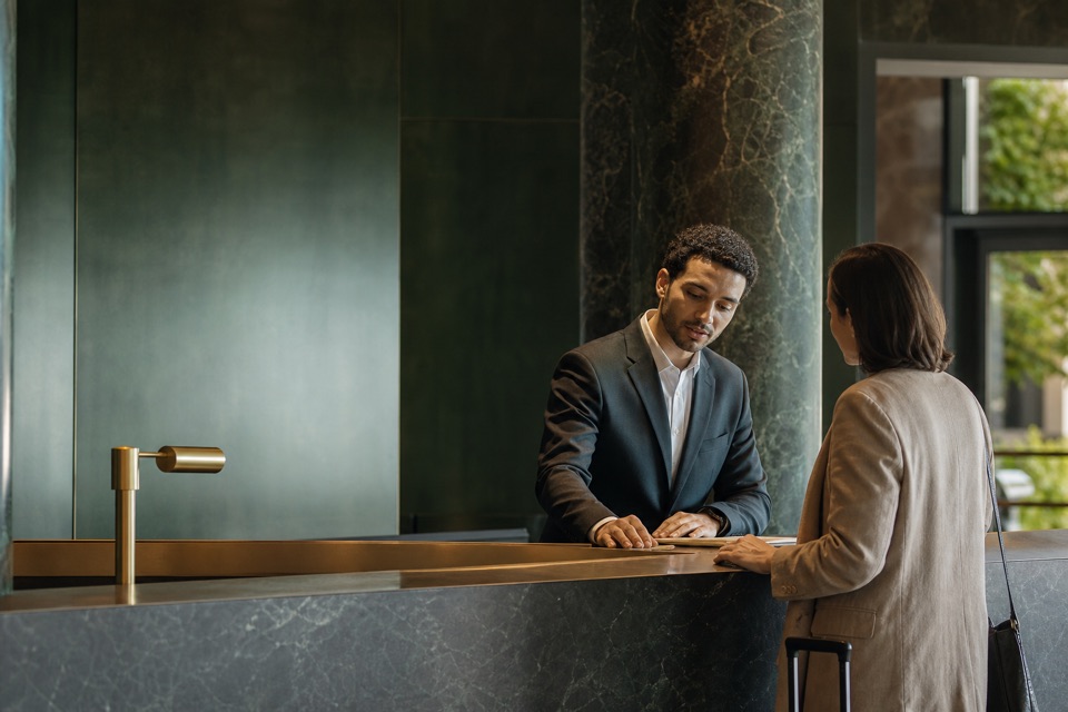 A concierge calmly helping a guest in a refined hotel reception